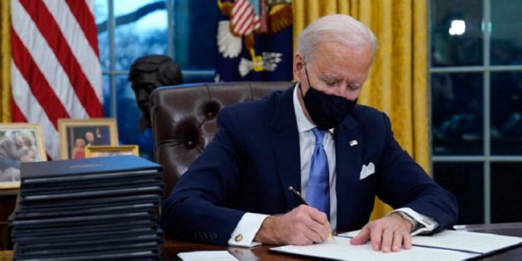 President Joe Biden signs his first executive order in the Oval Office of the White House on Wednesday, Jan. 20, 2021, in Washington. (AP Photo/Evan Vucci)